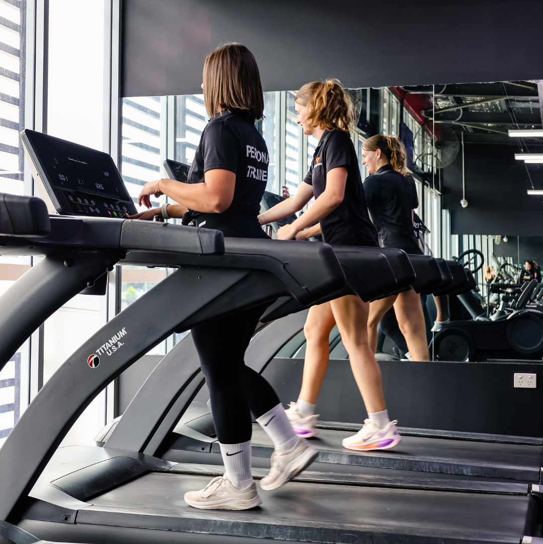 A personal trainer and her client on the treadmill together
